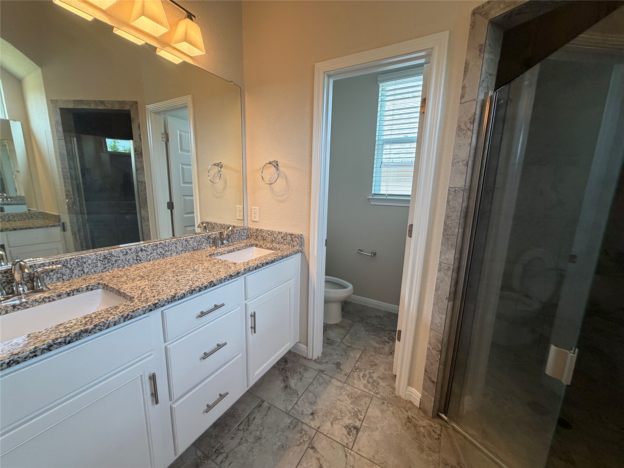 419 Gettysburg Loop Elgin, TX 78621 - Photo 8 of 21 Double vanity with granite counters and a glass-enclosed shower await in this well-appointed bathroom.