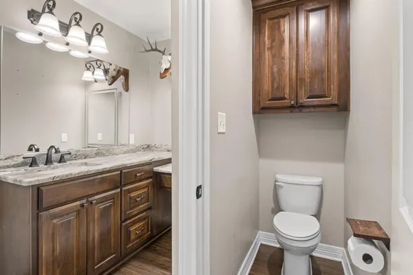a bathroom with a granite countertop toilet a sink and a mirror