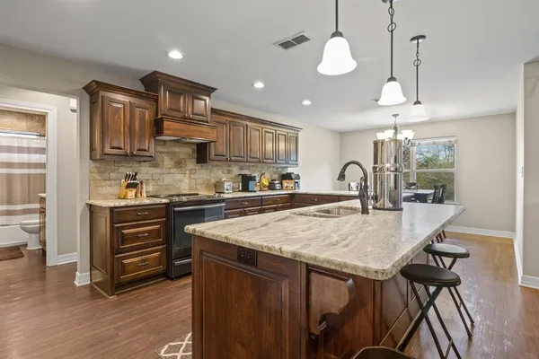 a kitchen with stainless steel appliances granite countertop a kitchen island a stove and a sink