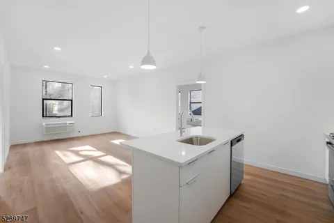 a kitchen with granite countertop a sink and dishwasher with wooden floor
