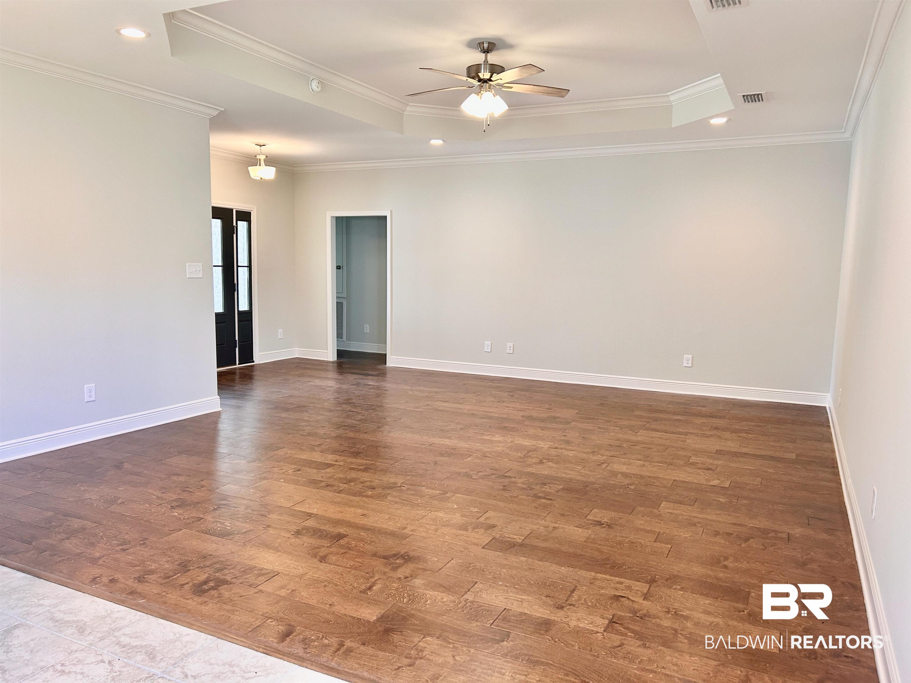1267 Pembroke Way Foley, AL 36535 - Photo 2 of 17 Spare room with crown molding, ceiling fan, dark hardwood / wood-style floors, and a tray ceiling