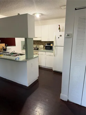 a kitchen with kitchen island white cabinets and refrigerator