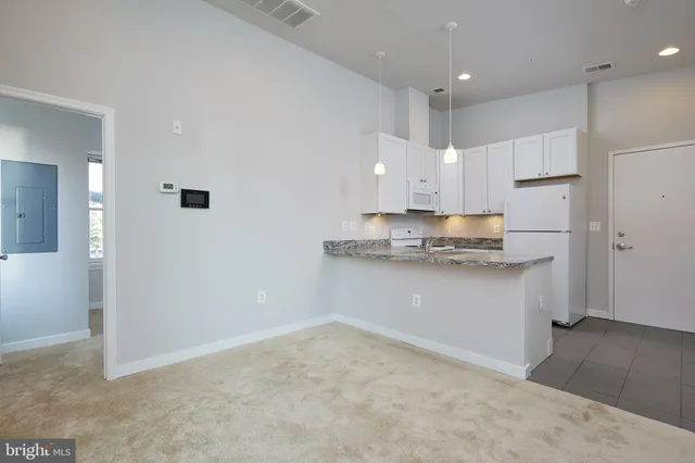 a kitchen with a refrigerator and white cabinets