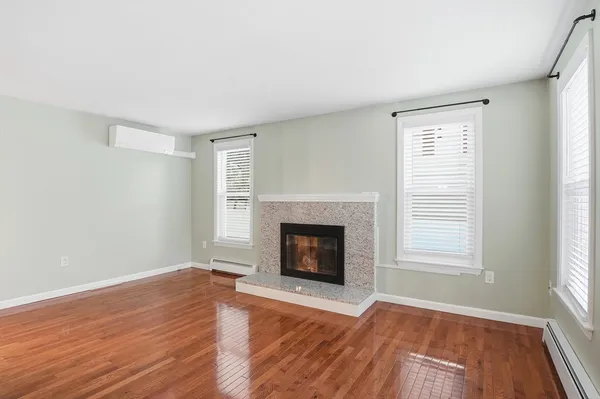 an empty room with wooden floor fireplace and windows