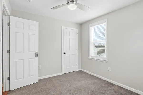 an empty room with windows and fan