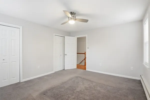 a view of an empty room and chandelier fan