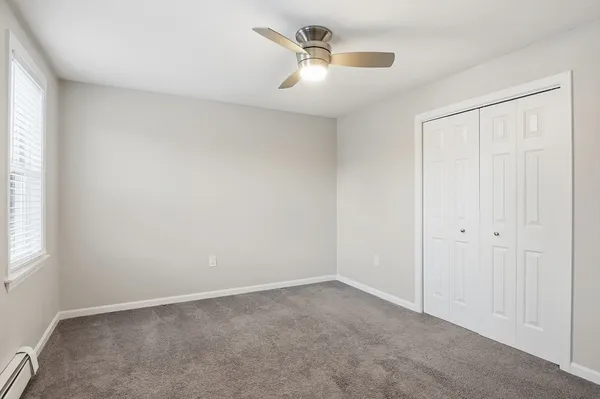 an empty room with a window and a ceiling fan