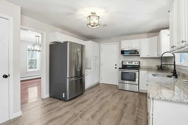 a kitchen with granite countertop a refrigerator cabinets and wooden floor