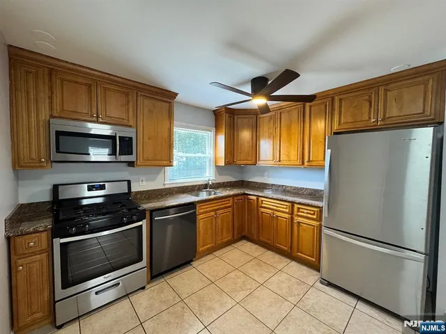a kitchen with granite countertop a refrigerator and a stove top oven