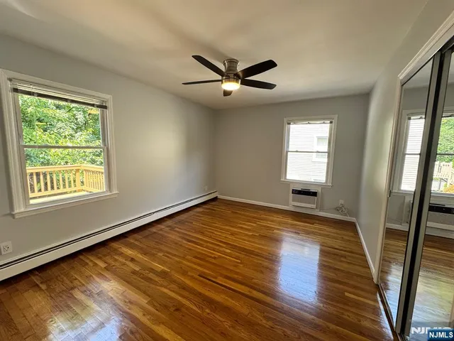 a view of empty room with wooden floor and fan
