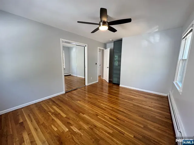 a view of empty room with wooden floor and fan