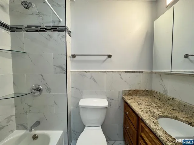 a bathroom with a granite countertop sink a toilet and shower