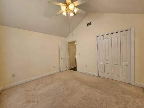 a view of an empty room with chandelier fan