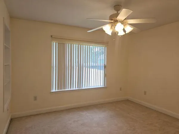 an empty room with a chandelier fan and windows
