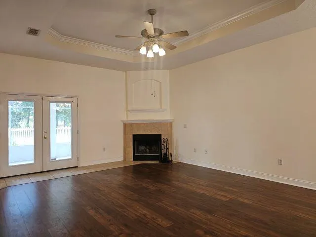 a view of an empty room with wooden floor fireplace and a window