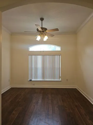 a view of an empty room with wooden floor a ceiling fan and a window