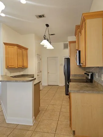 a kitchen with stainless steel appliances granite countertop a sink a stove a refrigerator a washer dryer and a dining table