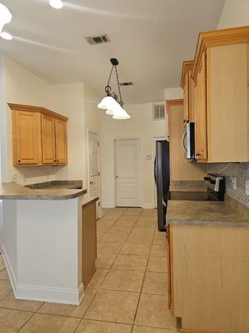 a kitchen with stainless steel appliances granite countertop a sink a stove a refrigerator a washer dryer and a dining table