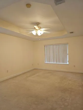 an empty room with a chandelier fan and windows