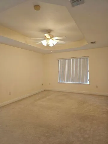 an empty room with a chandelier fan and windows
