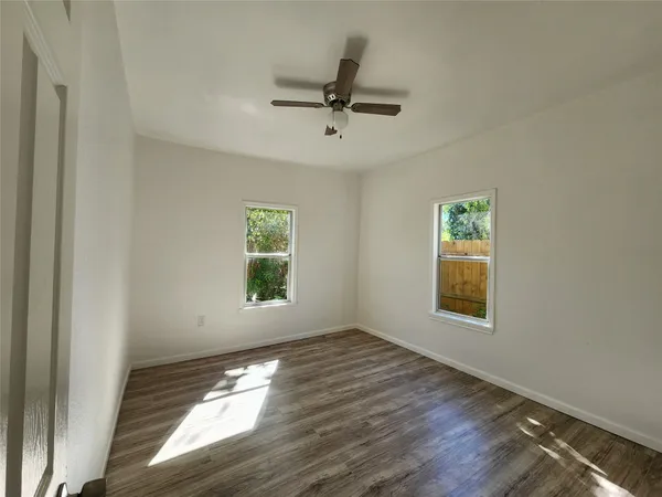 a view of empty room with wooden floor and fan