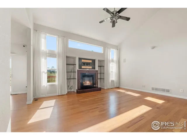 a view of an empty room with a window and kitchen view