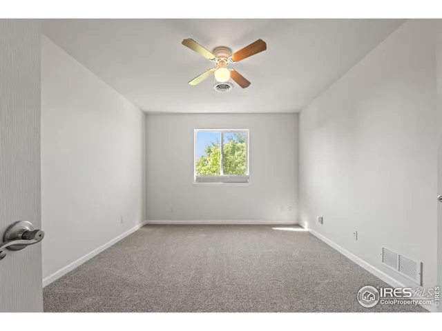 a view of an empty room with a chandelier fan