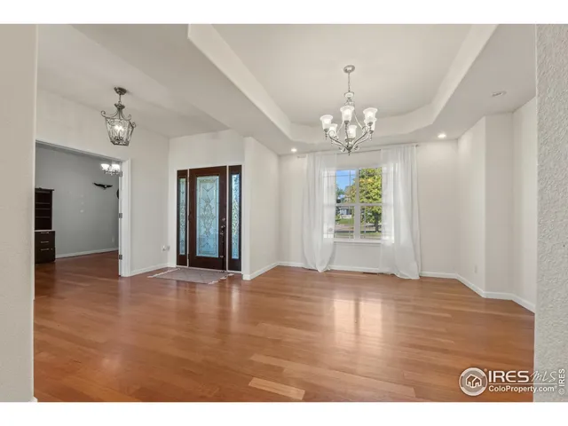 a view of an empty room with window and hardwood floor