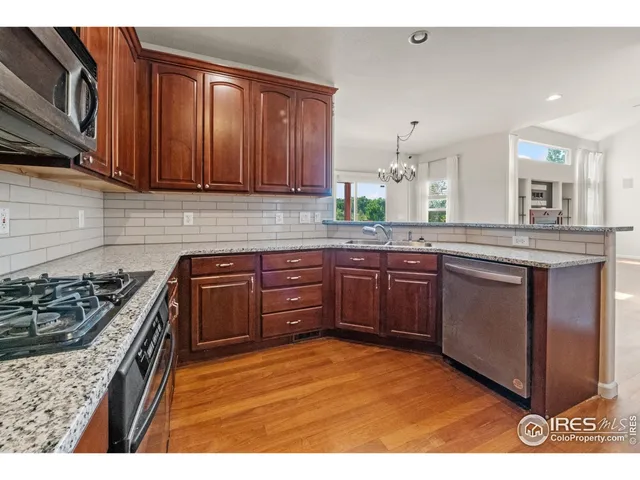 a kitchen with stainless steel appliances granite countertop a stove a sink dishwasher and cabinets with wooden floor