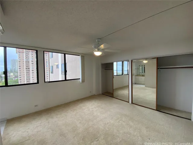 an empty room with chandelier fan and windows