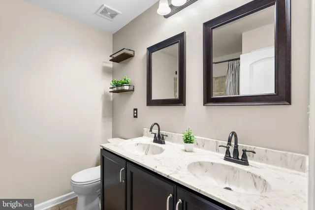 a bathroom with a granite countertop sink and a toilet