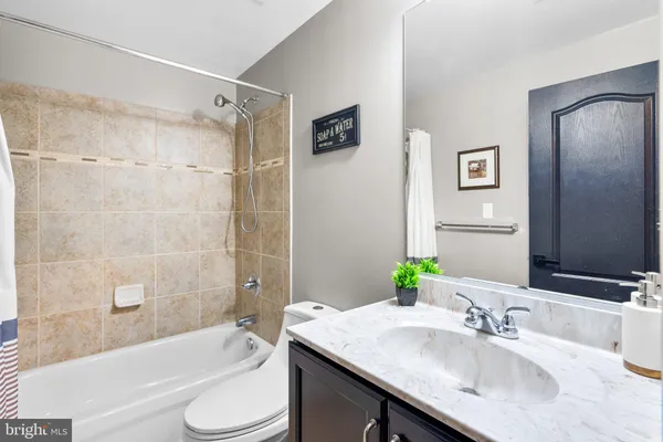 a bathroom with a granite countertop bathtub shower sink vanity mirror and toilet