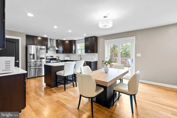 a kitchen with stainless steel appliances kitchen island granite countertop a sink a stove a refrigerator with a dining table and chairs