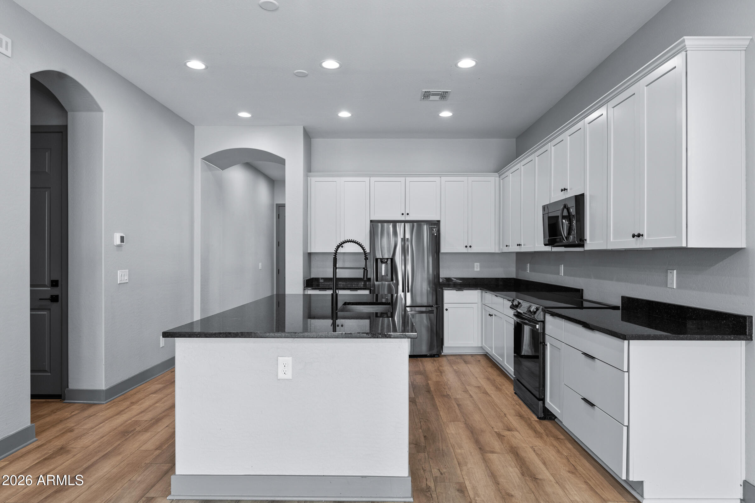 3900 East Appaloosa Road Gilbert, AZ 85296 - Photo 12 of 38 a kitchen with stainless steel appliances granite countertop a stove a sink a refrigerator and white cabinets with wooden floor