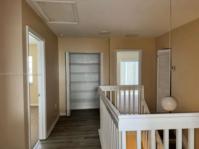 a view of a hallway with entryway and wooden floor