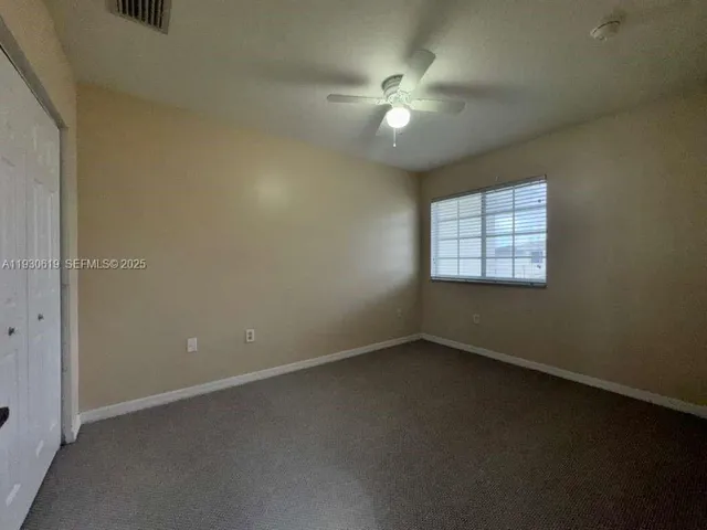 an empty room with a chandelier fan and windows
