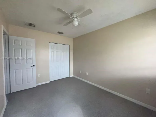 an empty room with a ceiling fan and a window