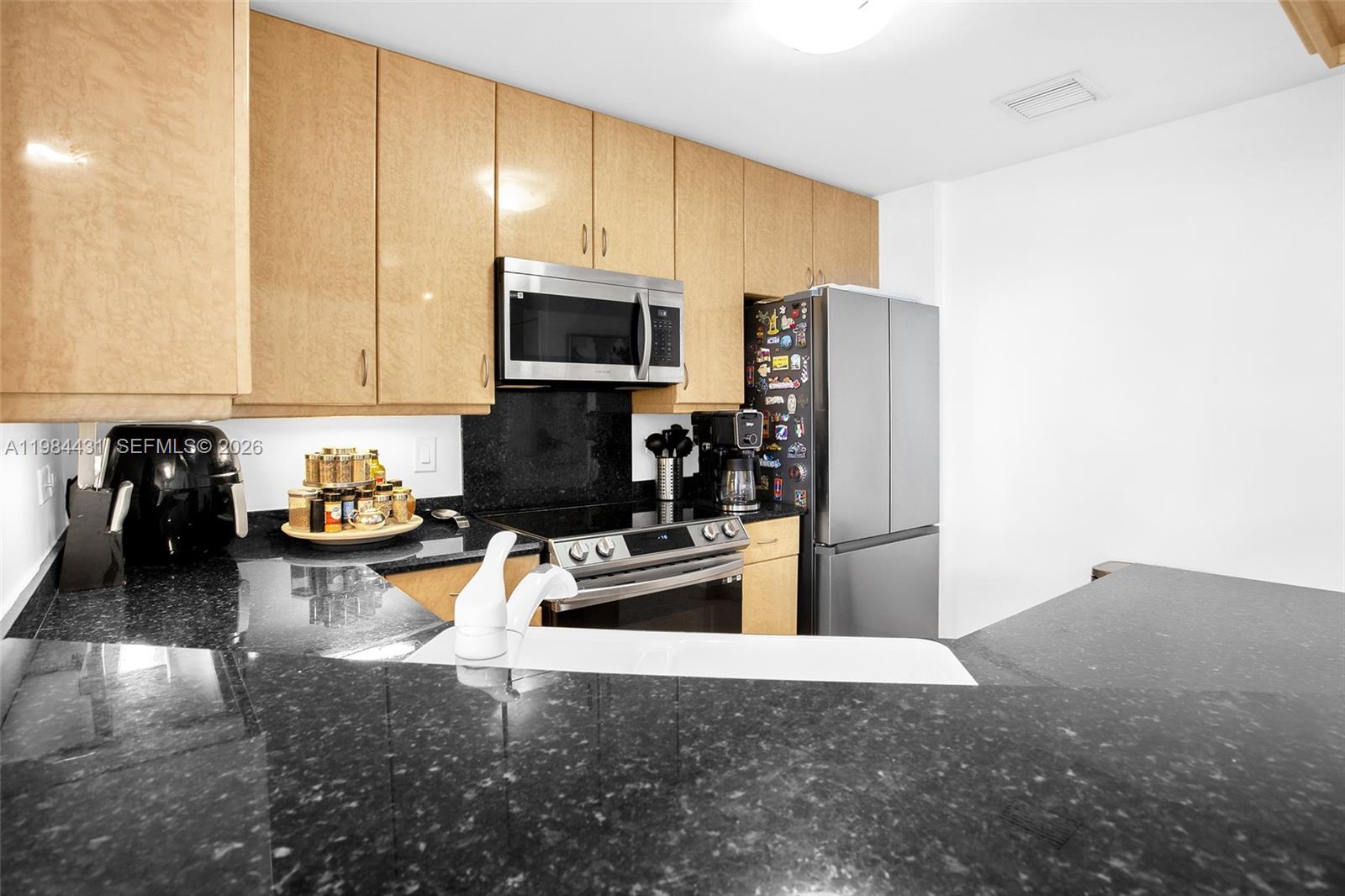 801 Brickell Key Boulevard, Unit 907 Miami, FL 33131 - Photo 15 of 53 a kitchen with stainless steel appliances a stove a sink a refrigerator white cabinets and wooden floor
