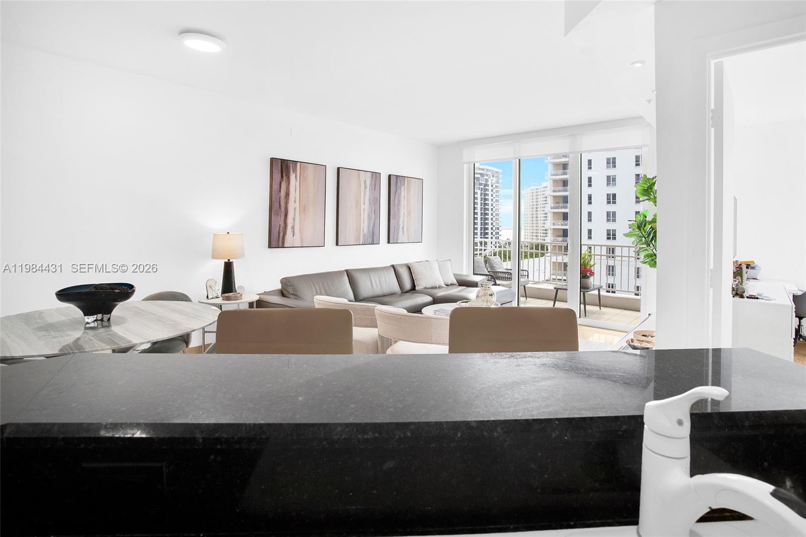 801 Brickell Key Boulevard, Unit 907 Miami, FL 33131 - Photo 16 of 53 a living room with large couches and kitchen view with wooden floor