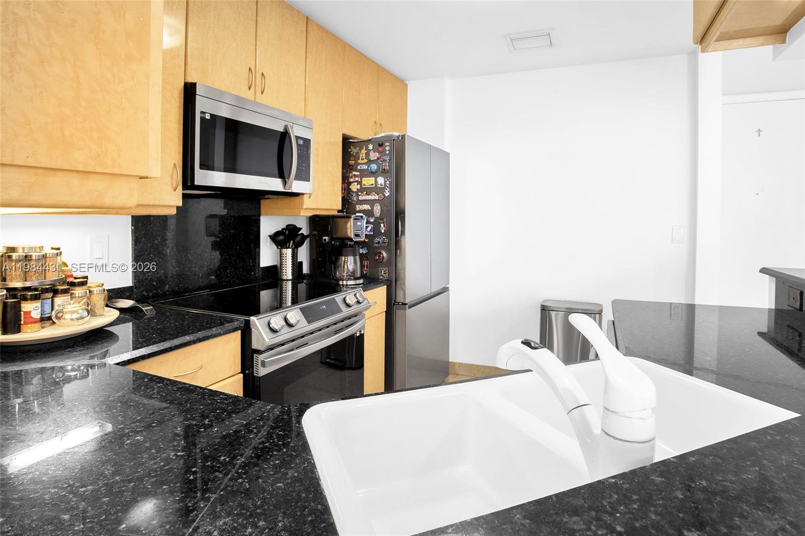 801 Brickell Key Boulevard, Unit 907 Miami, FL 33131 - Photo 17 of 53 a kitchen with stainless steel appliances granite countertop a sink dishwasher a stove top oven a dining table and chairs with wooden floor