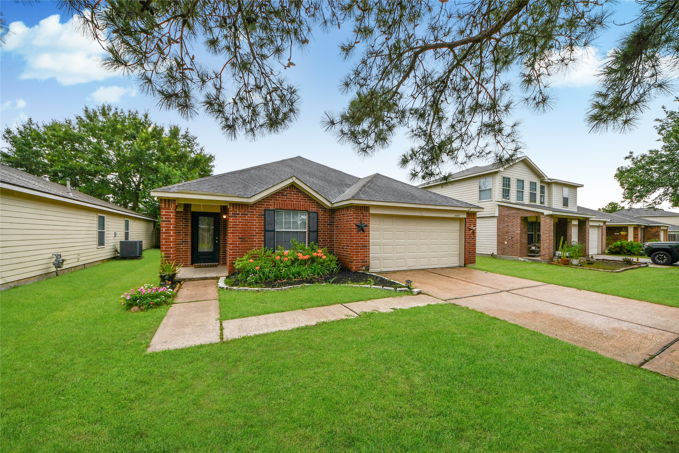 24019 Kingbriar Drive Spring, TX 77373 - Photo 5 of 41 A charming full-frontal shot under a blue sky, framing the attractive brick veneer, well-tended garden beds with colorful blooms, and the stately mature tree that enhances this lovely home.