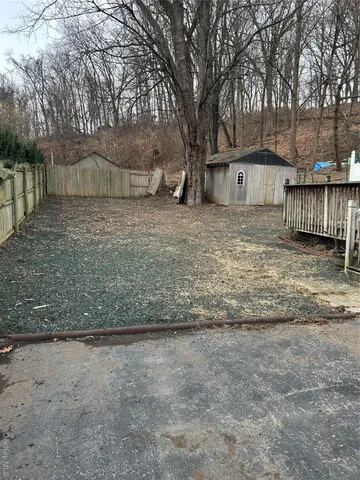 a view of a yard with wooden fence and a large tree