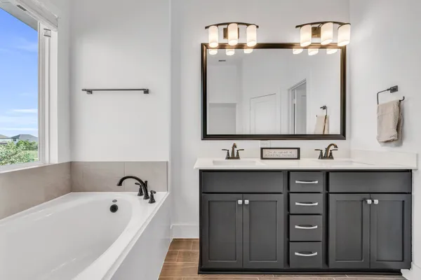 a bathroom with a bathtub a double vanity sink and mirror