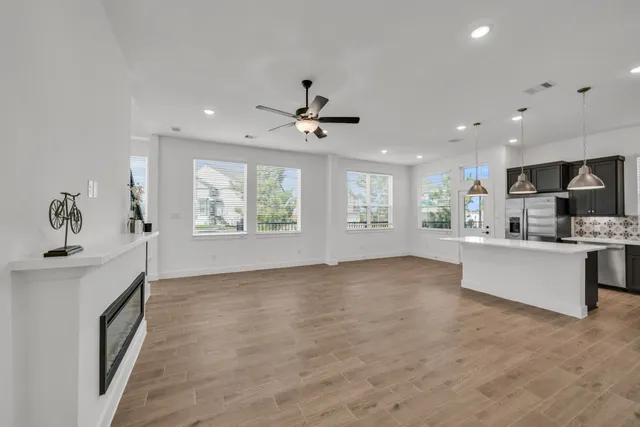 a view of an empty room with a window and kitchen view