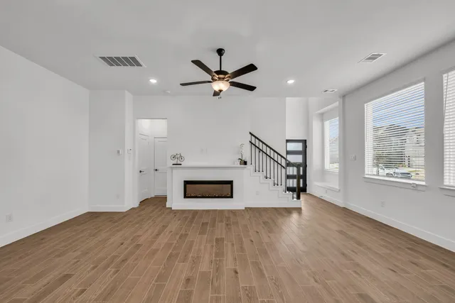 a view of empty room with wooden floor and a ceiling fan