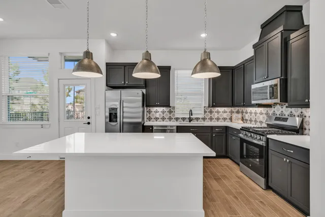 a large kitchen with stainless steel appliances kitchen island granite countertop a sink a stove and a wooden cabinets