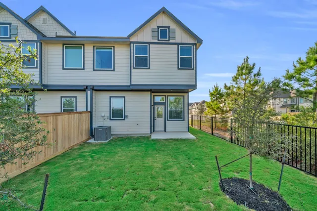 a view of a yard in front of a house with plants and large tree