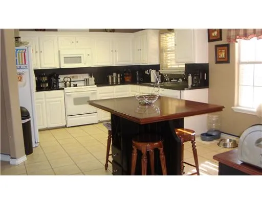 a kitchen with stainless steel appliances kitchen island granite countertop a sink a stove a dining table and chairs