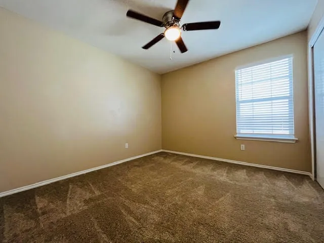 an empty room with a window and a ceiling fan