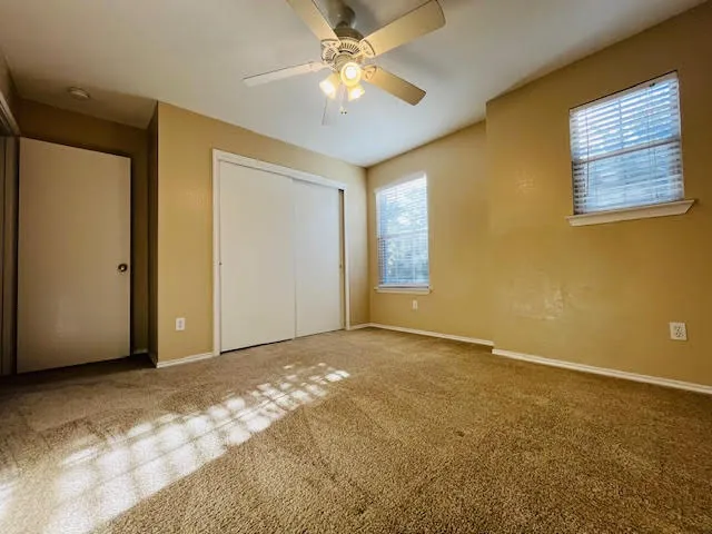 a view of an empty room with window and chandelier fan